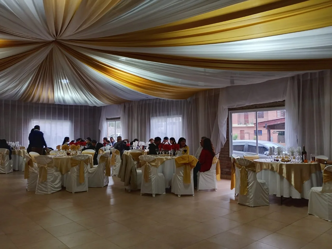 Salón preparado con mesas vestidas para un evento familiar